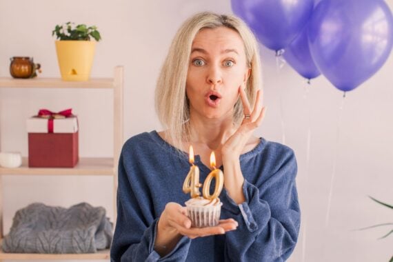 Middle aged woman looks with surprise at the number forty on the birthday cake