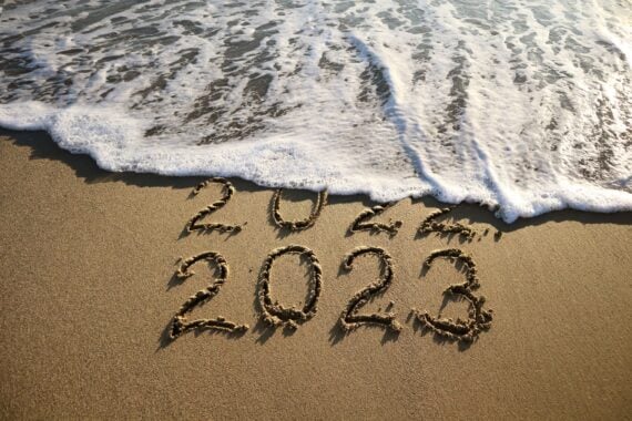 New year 2023 and old year 2022 written on sandy beach with waves