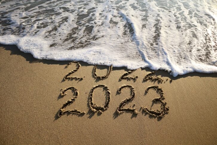 New year 2023 and old year 2022 written on sandy beach with waves