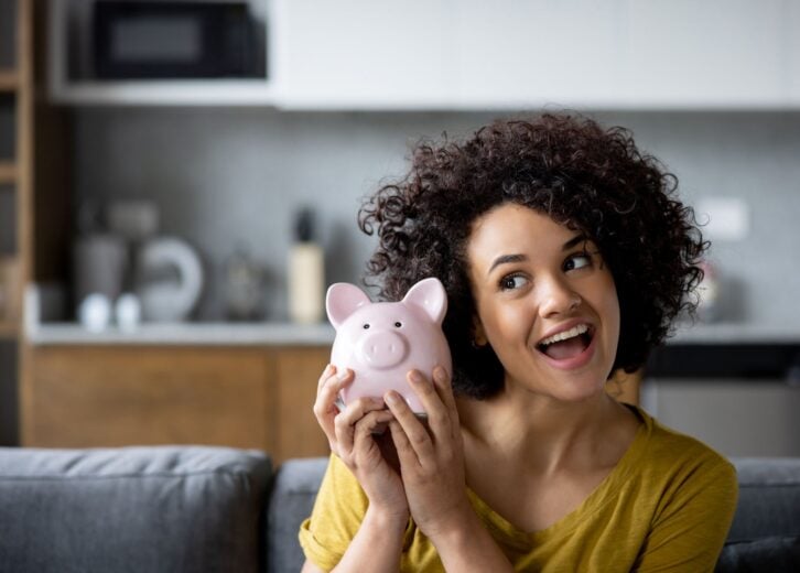 Portrait of a Latin American woman at home ready to open her piggy bank - home finances concepts