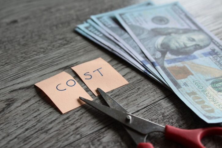 Scissor, money and note with text COST. Financial, cost cutting, reduce expenses concept