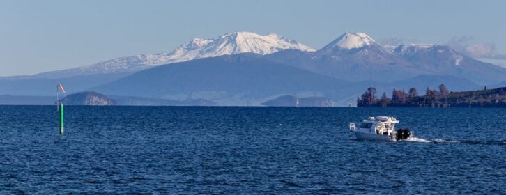 Boat at the lake Taupo, volcanoes at the background. New Zealand
