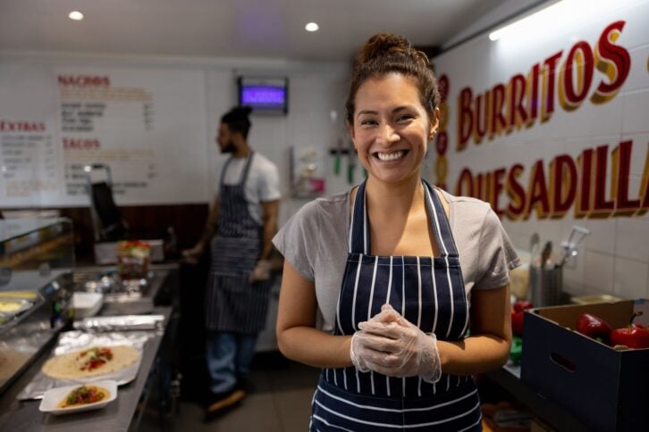 Portrait of a happy woman working at a small Mexican restaurant and looking at the camera smiling - food service concepts