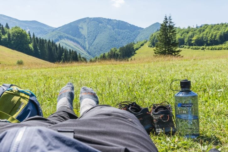 Terchova, Slovakia - July 24, 2022: Resting tourist on green grass after exhausting trip on a hot day.