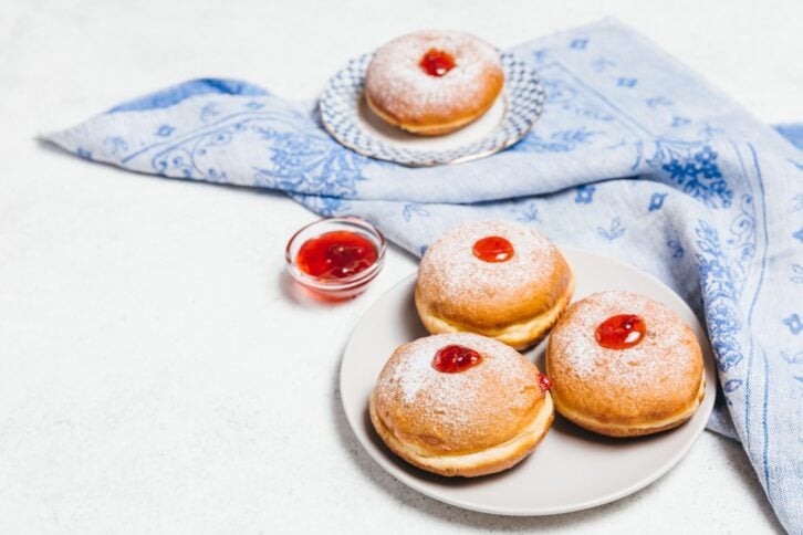 Sufganiyot jelly doughnuts cooked in oil on white table background. Traditional Jewish festive food dessert for Hanukkah holiday. Flat lay, top view