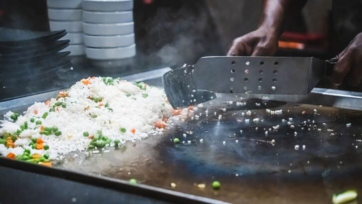 Teppanyaki chef entertaining with spatulas