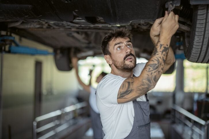 Portrait of a mechanic repairing a lifted car