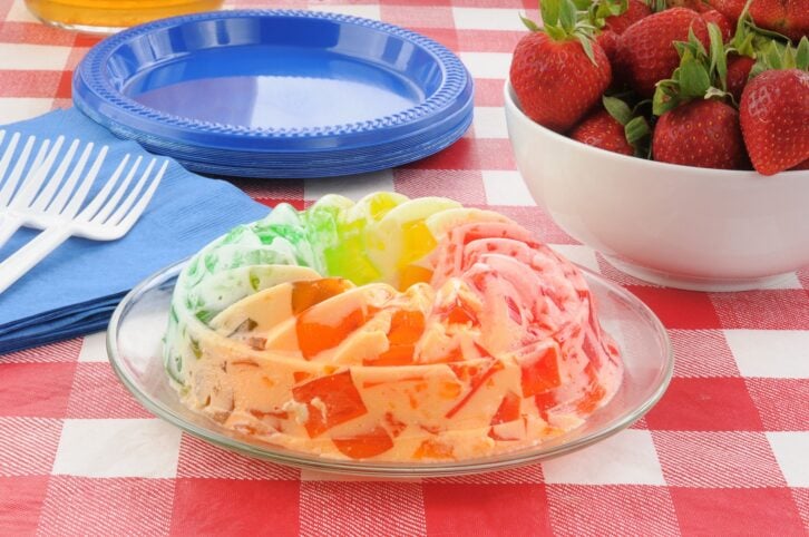 A parfait with cubes of fruit gelatin and a bowl of strawberries