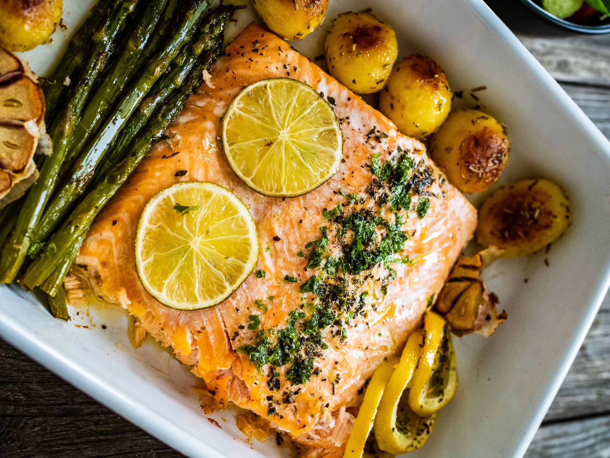 Roasted salmon steak, roasted potatoes and asparagus on wooden table