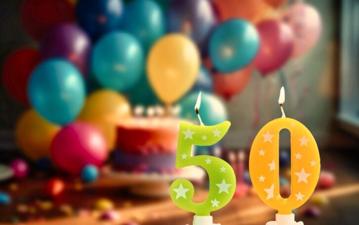 Happy birthday card with candle number 50 against festive background with balloons and Birthday cake. Copy space happy birthday for fifty years. Celebrating space for text