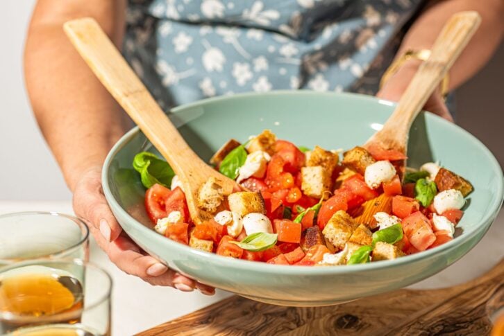 A woman holding a bowl of classic Panzanella salad.