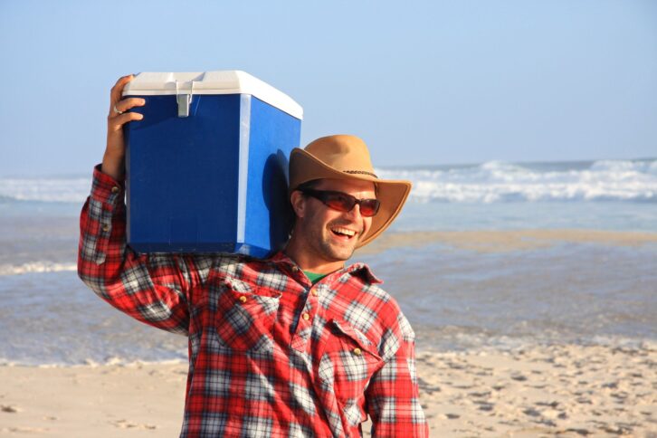 Close up of a happy young man laughing. He is carrying an esky on his shoulder. (This picture is taken in Denmark, Western Australia)