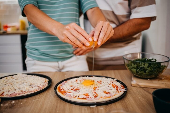 Couple preparing pizza at home in the kitchen