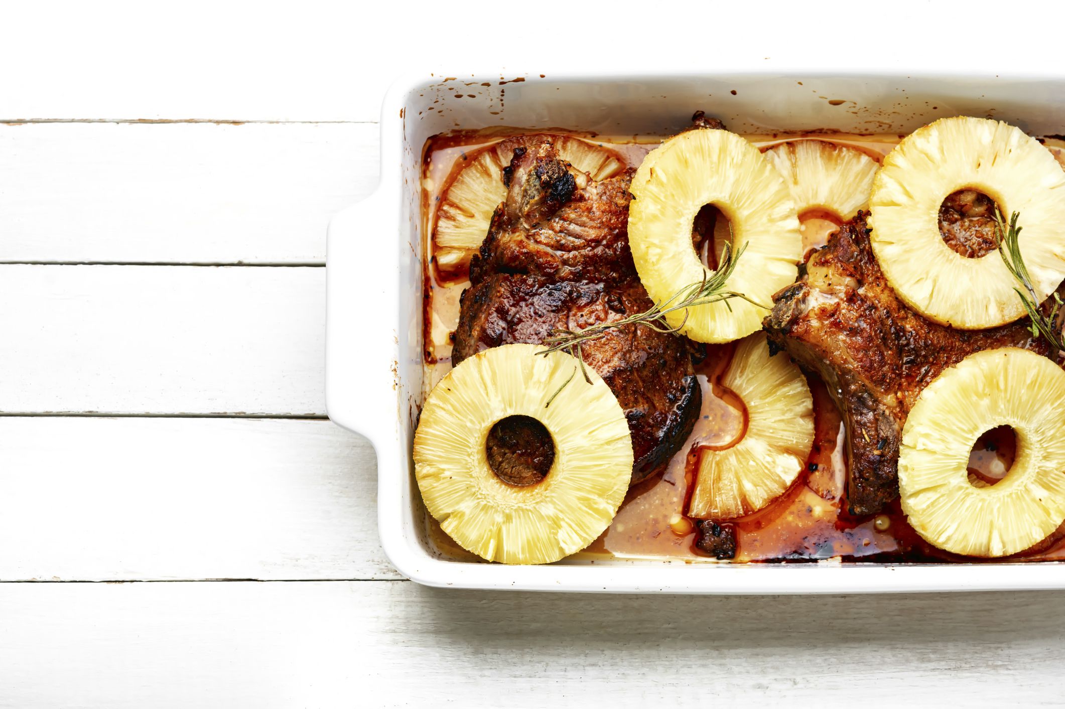 Meat steak on the rib fried with pineapple. Fruit and meat in baking dish.