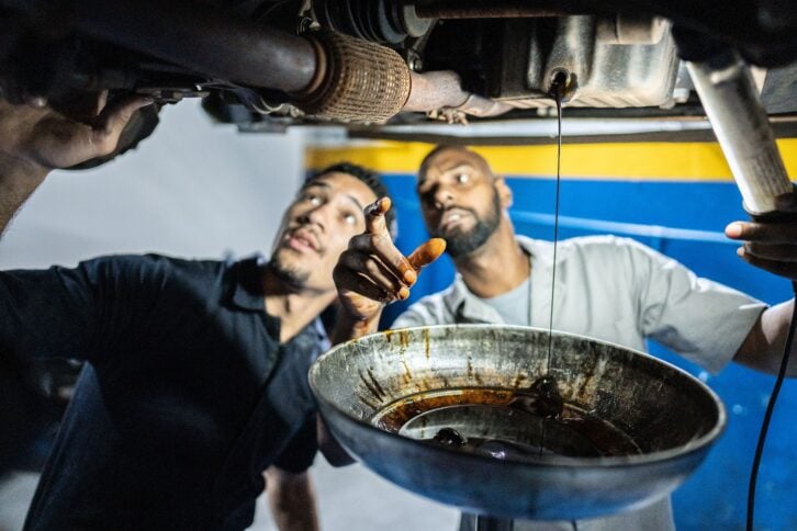 Mechanics talking while looking the car in an auto repair shop