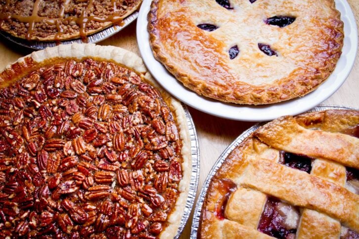 Lattice Crust Fruit Pie closeup on wooden table including apple caramel, apple berry, pecan and blueberry pies