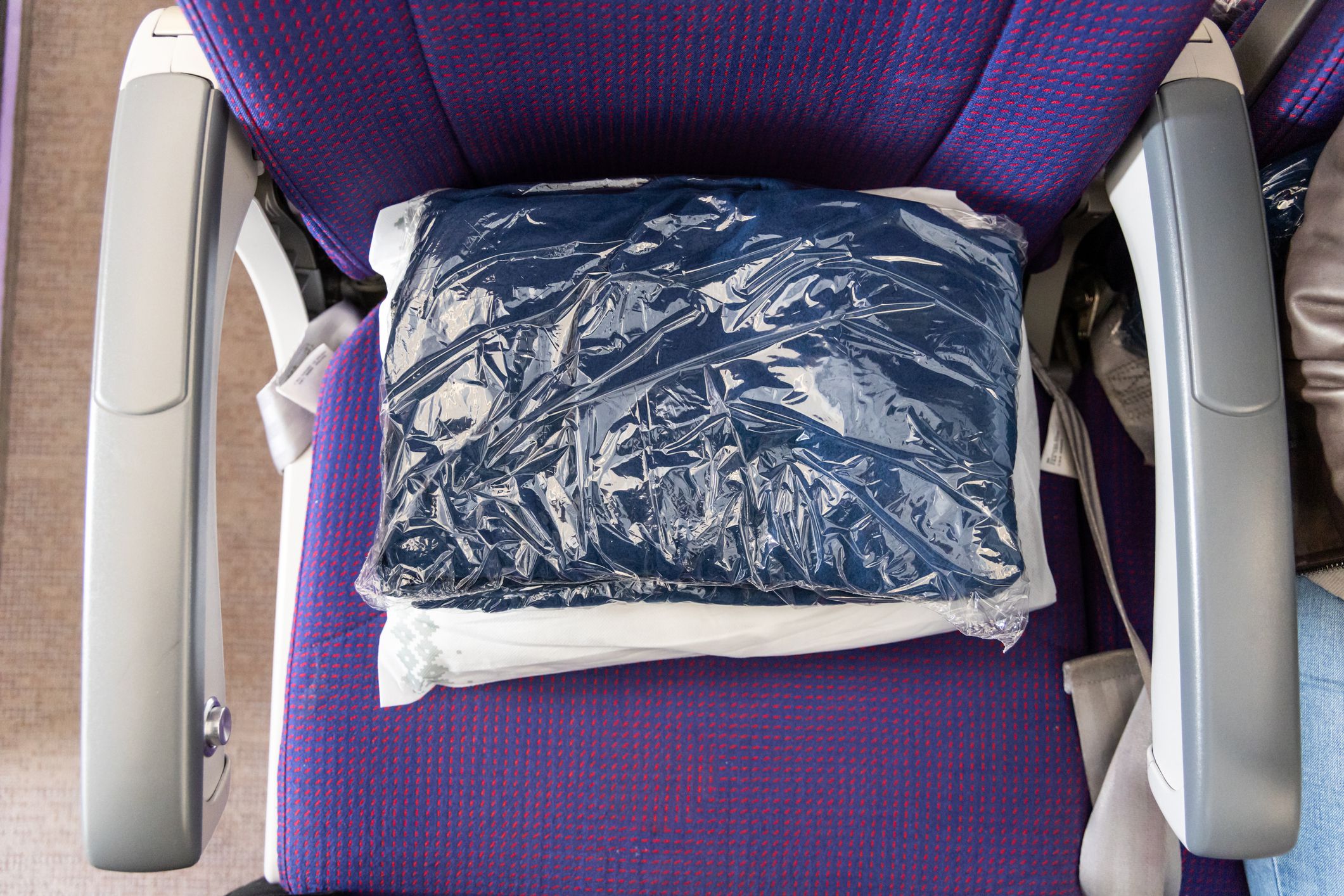 Sanitized and sealed wool blanket in plastic bag provided to passengers to keep warm and comfortable during long-haul flight