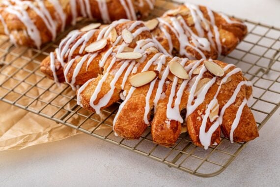 Bear claw pastry on a cooling rack with glaze and sliced almonds