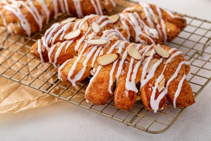Bear claw pastry on a cooling rack with glaze and sliced almonds
