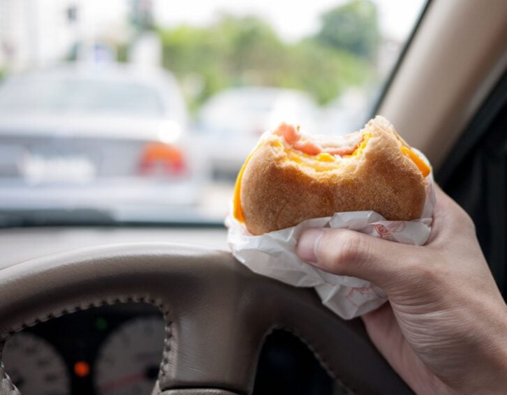Driver eating burger in the car as the traffic is very bad in the morning. Abstract of urban life.