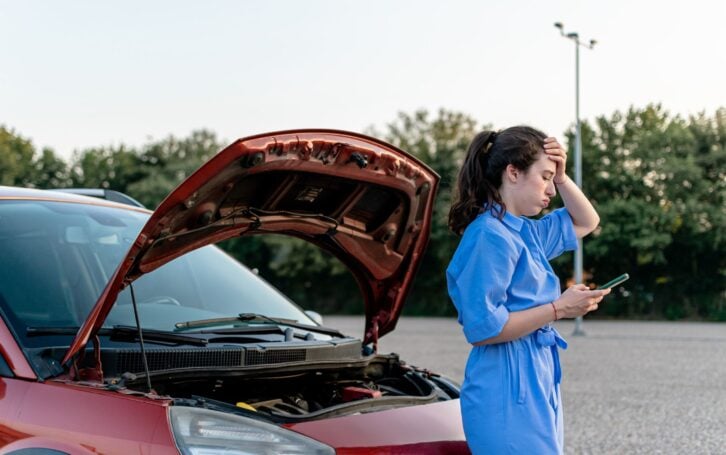 Facing a car breakdown, a resourceful young woman utilizes her phone to send an SMS, seeking prompt help to resolve the situation and get back on track