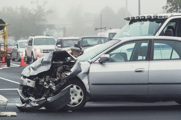 Heavy traffic backs up on the scene of an accident in foggy conditions.