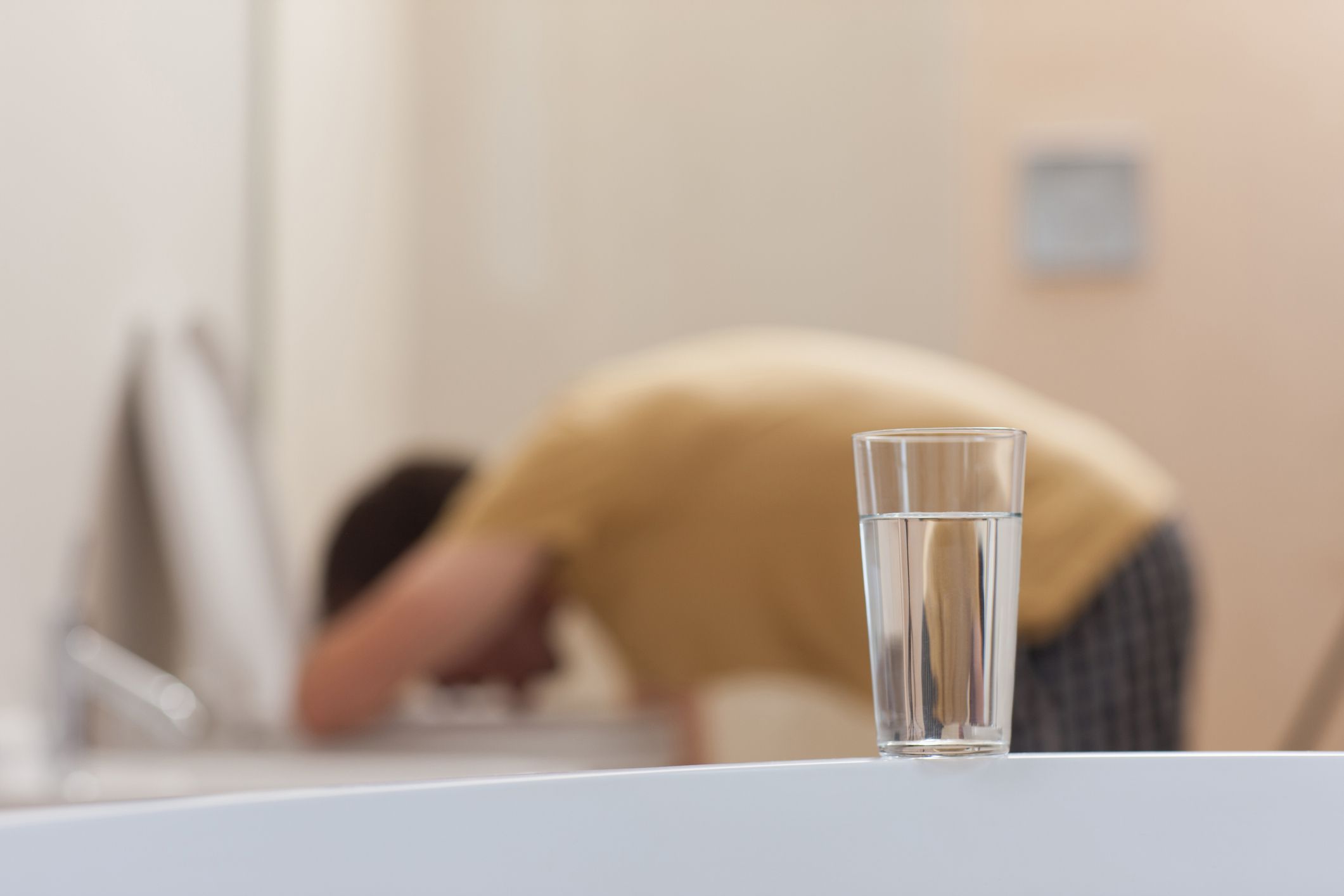 glass of water with vomiting man in background