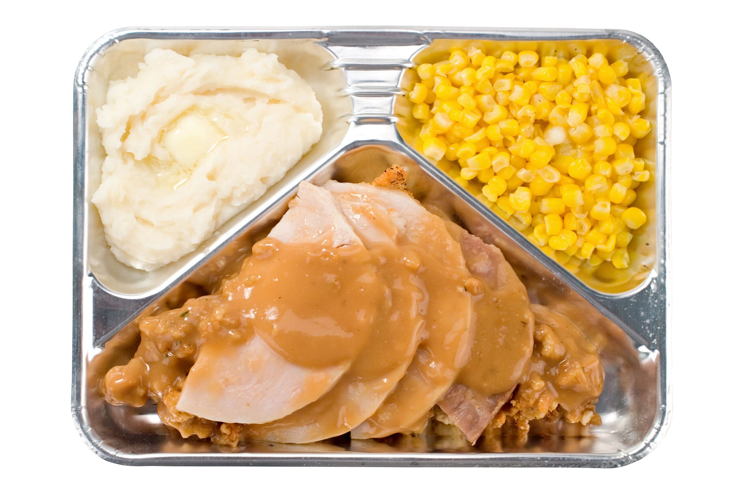 The bachelors lonely holiday standby meal. Classic turkey TV dinner in a retro aluminum tray. Isolated.