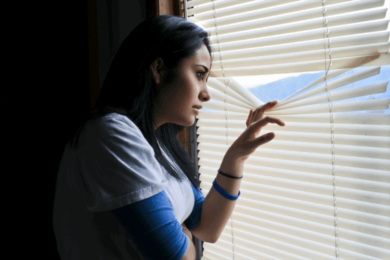 paranoid woman looking through blinds
