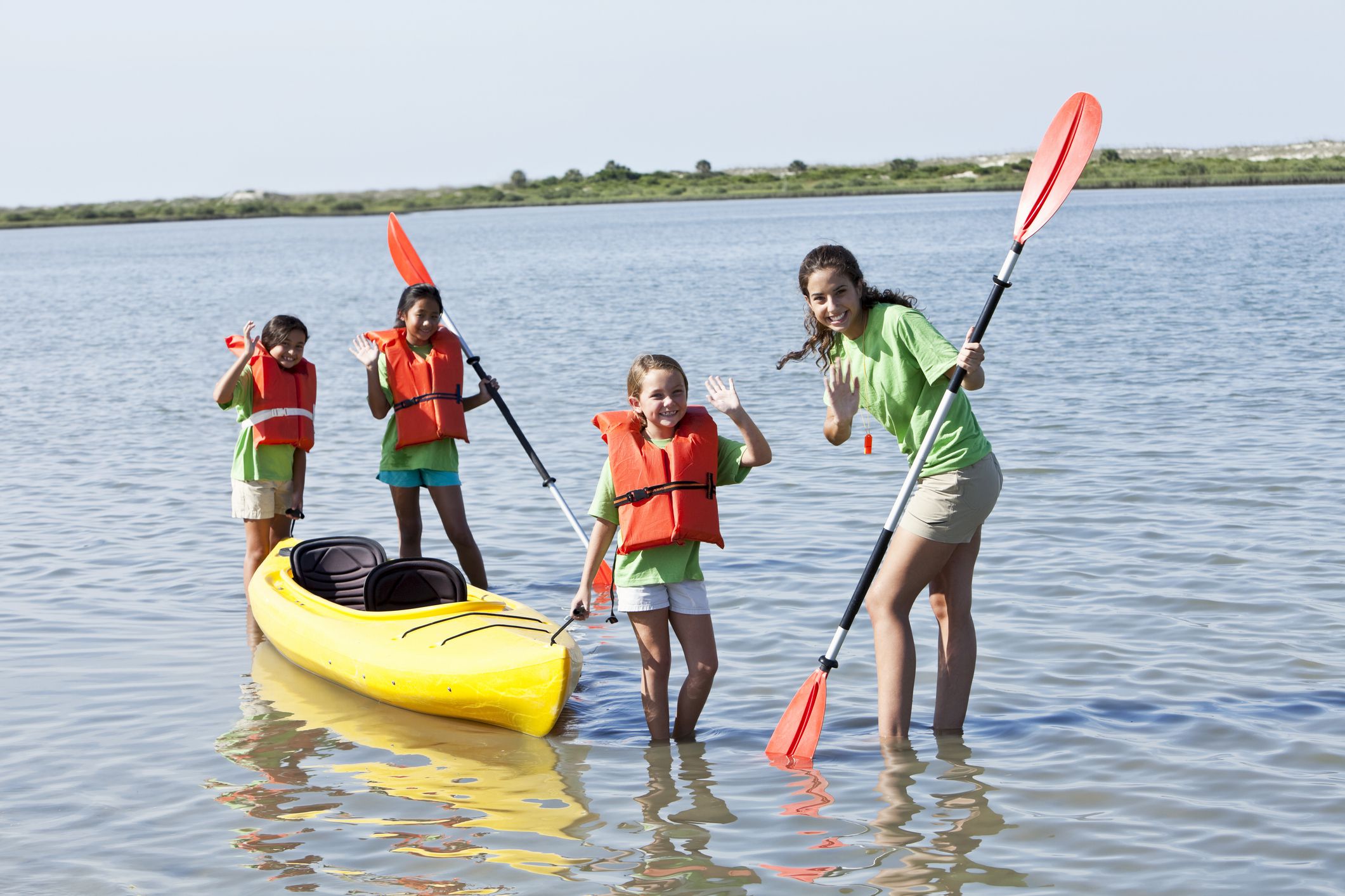 Multi-ethnic girls with kayak. Focus on teenage girl (17 years) and child (8 years) in foreground.