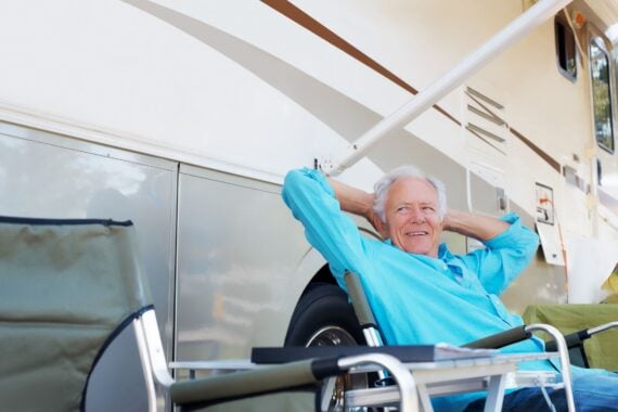 senior man leaning back smiling sitting outside rv