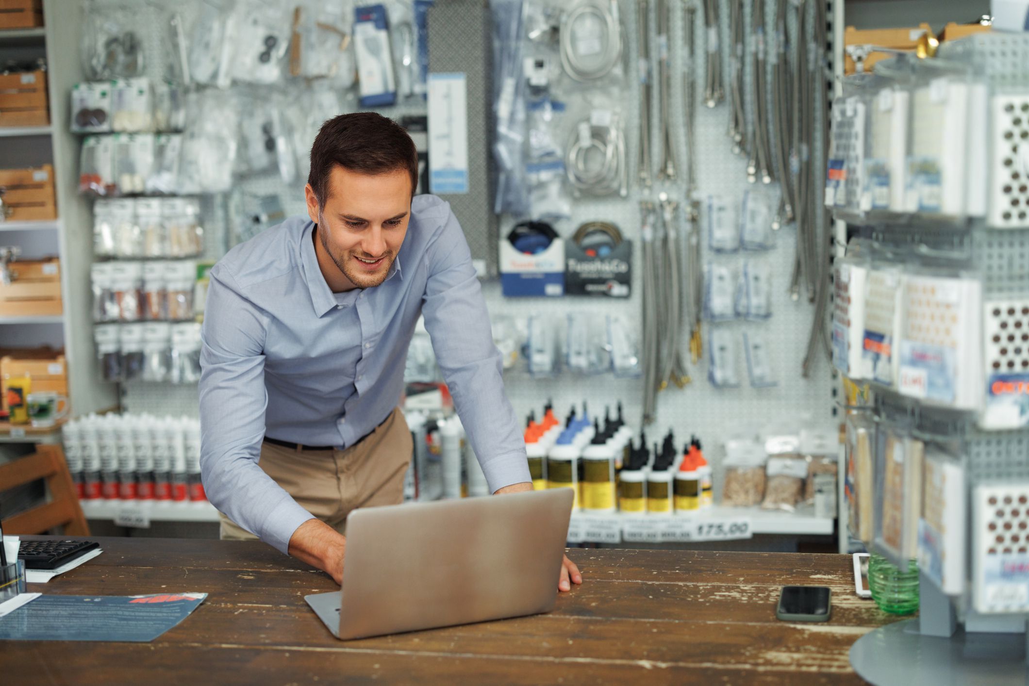 Young handsome man using laptop while working at hardware store