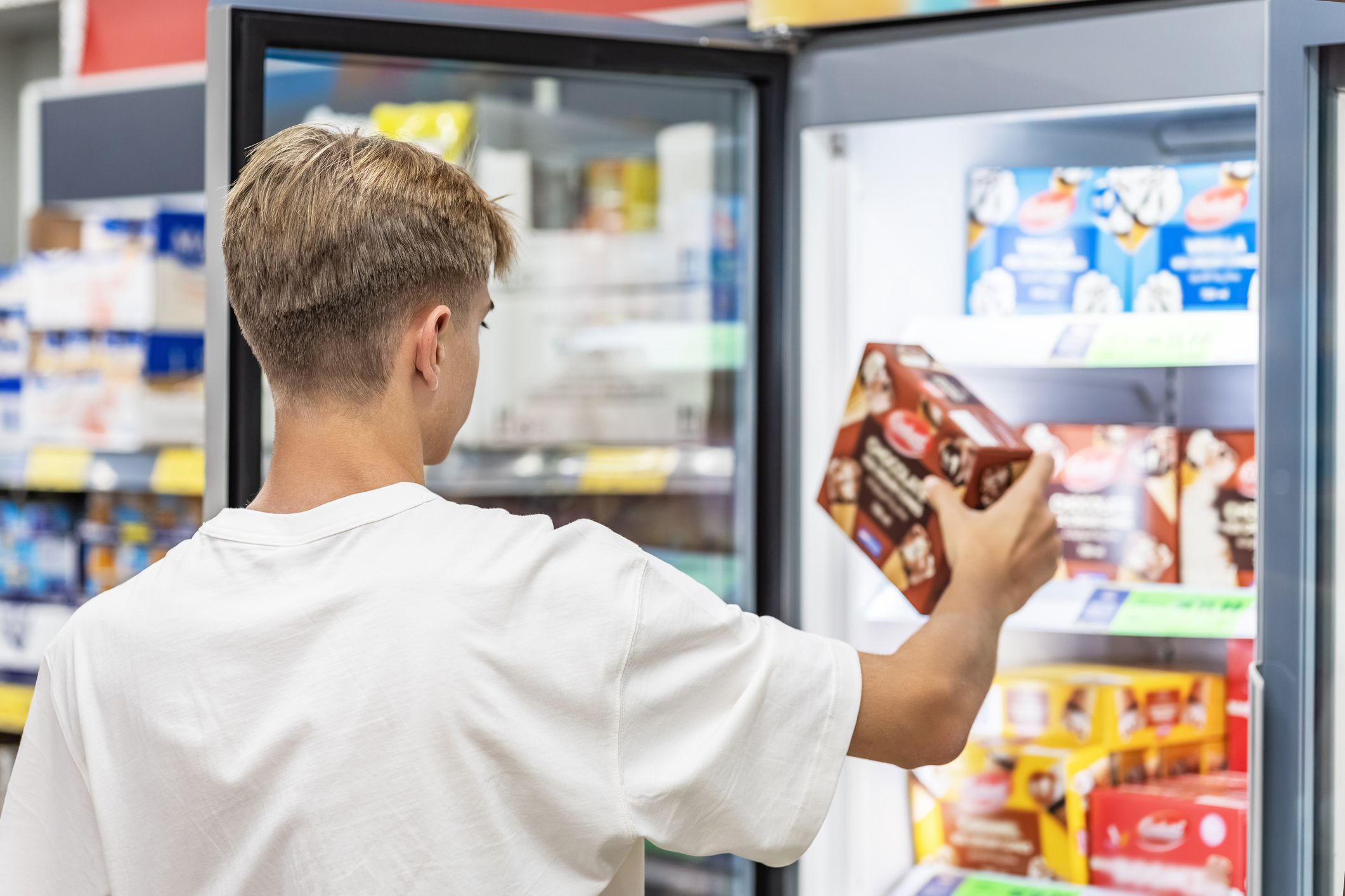 Man choosing frozen food from a supermarket freezer . ice cream,