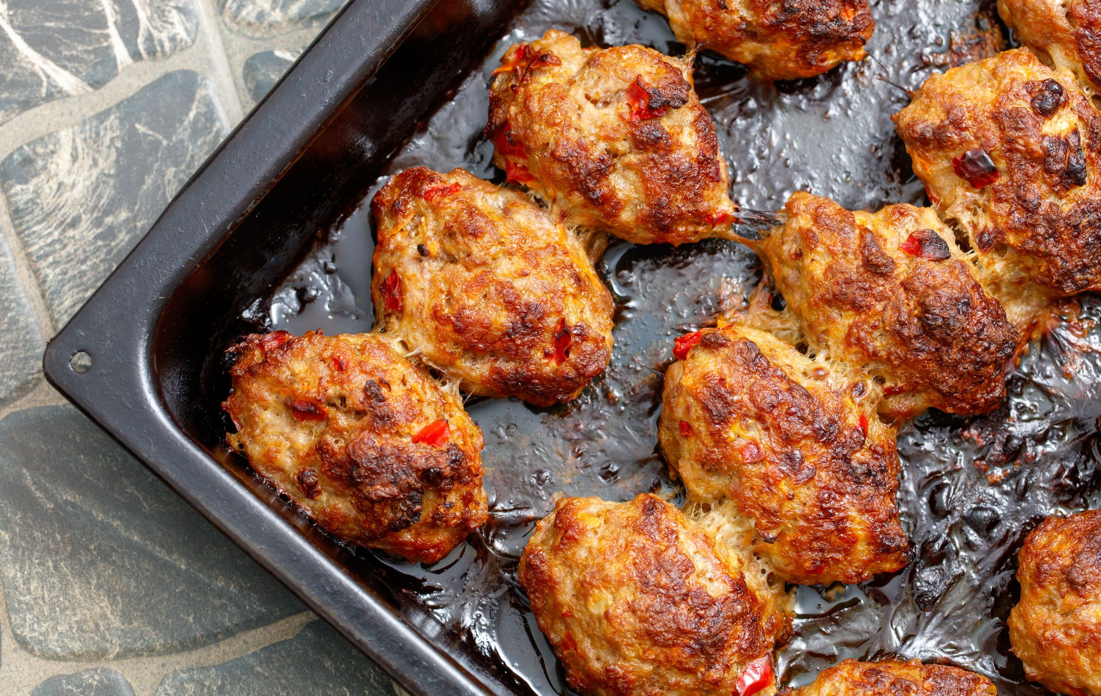 A tray of meatballs is sitting on a counter. The meatballs are brown and have a crispy texture