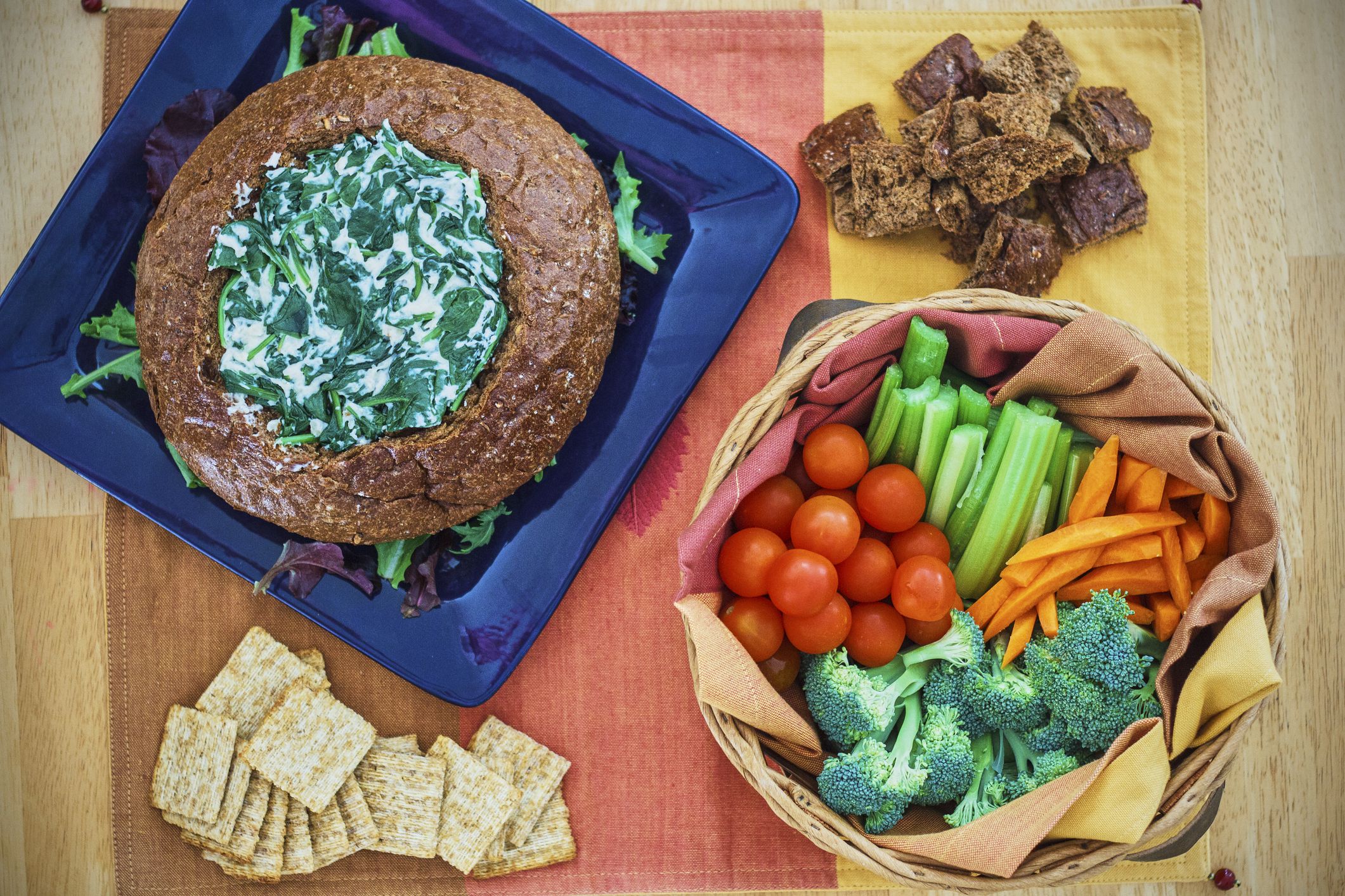 fresh spinach dip served in a bread bowl with assorted vegetables for dipping
