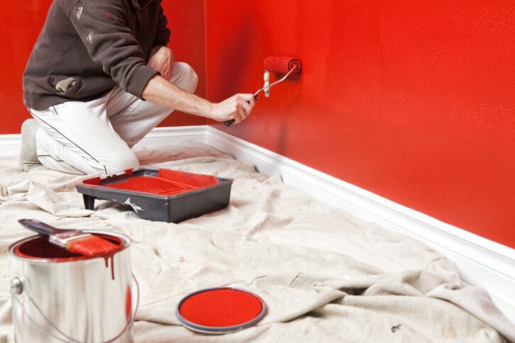 Person painting a wall red.