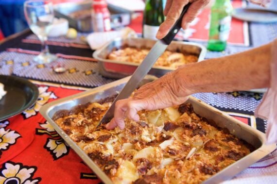 Close up elderly woman hands holding knife to cut a slice of homemade food