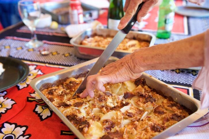 Close up elderly woman hands holding knife to cut a slice of homemade food