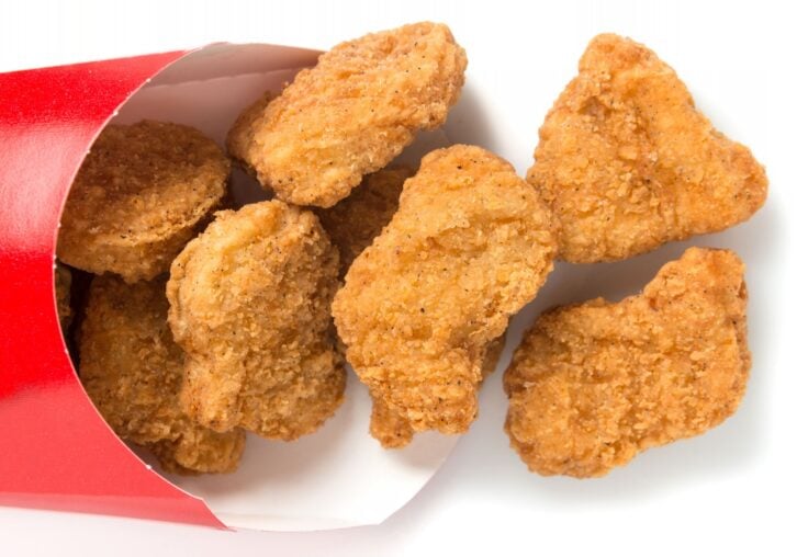 Chicken nuggets coming out of the package on white background