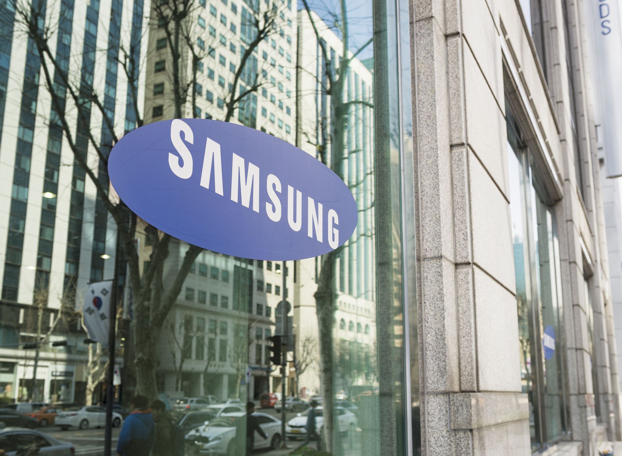 Seoul, Republic of Korea - March 26, 2013: The Samsung logo on the window of one of the South Korean company's offices in Gangnam, central Seoul, with cars and people on the street reflected in the window.