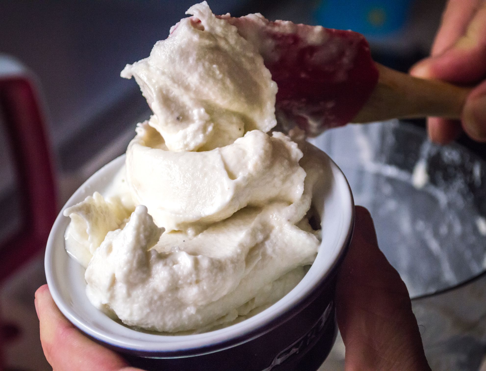 A male hand serving up freshly made homemade ice-cream into a small ramekin.