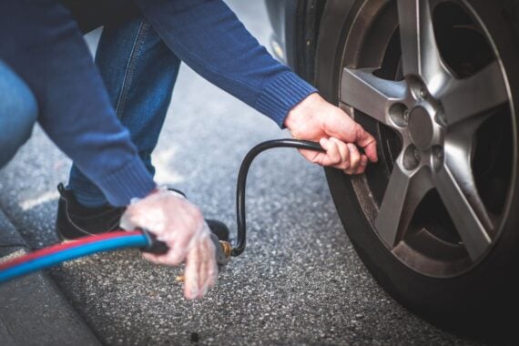 adult checking pressure and inflating car tire