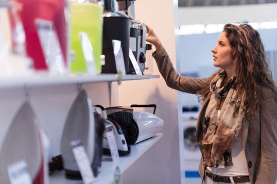 Beautiful woman choosing new electric juicer in homeware store