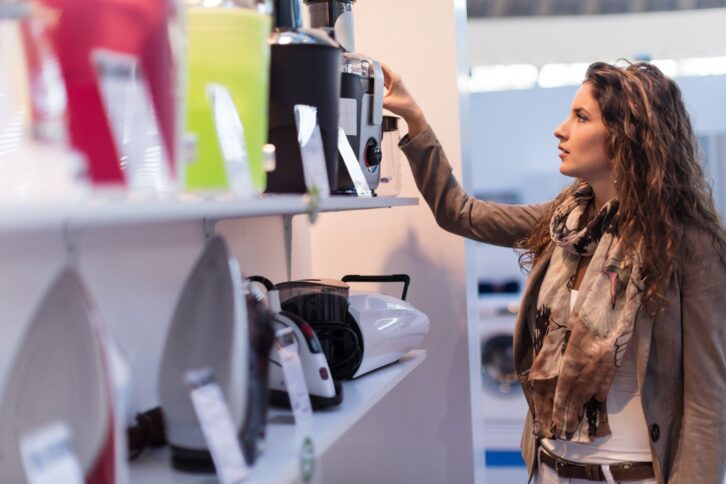 Beautiful woman choosing new electric juicer in homeware store