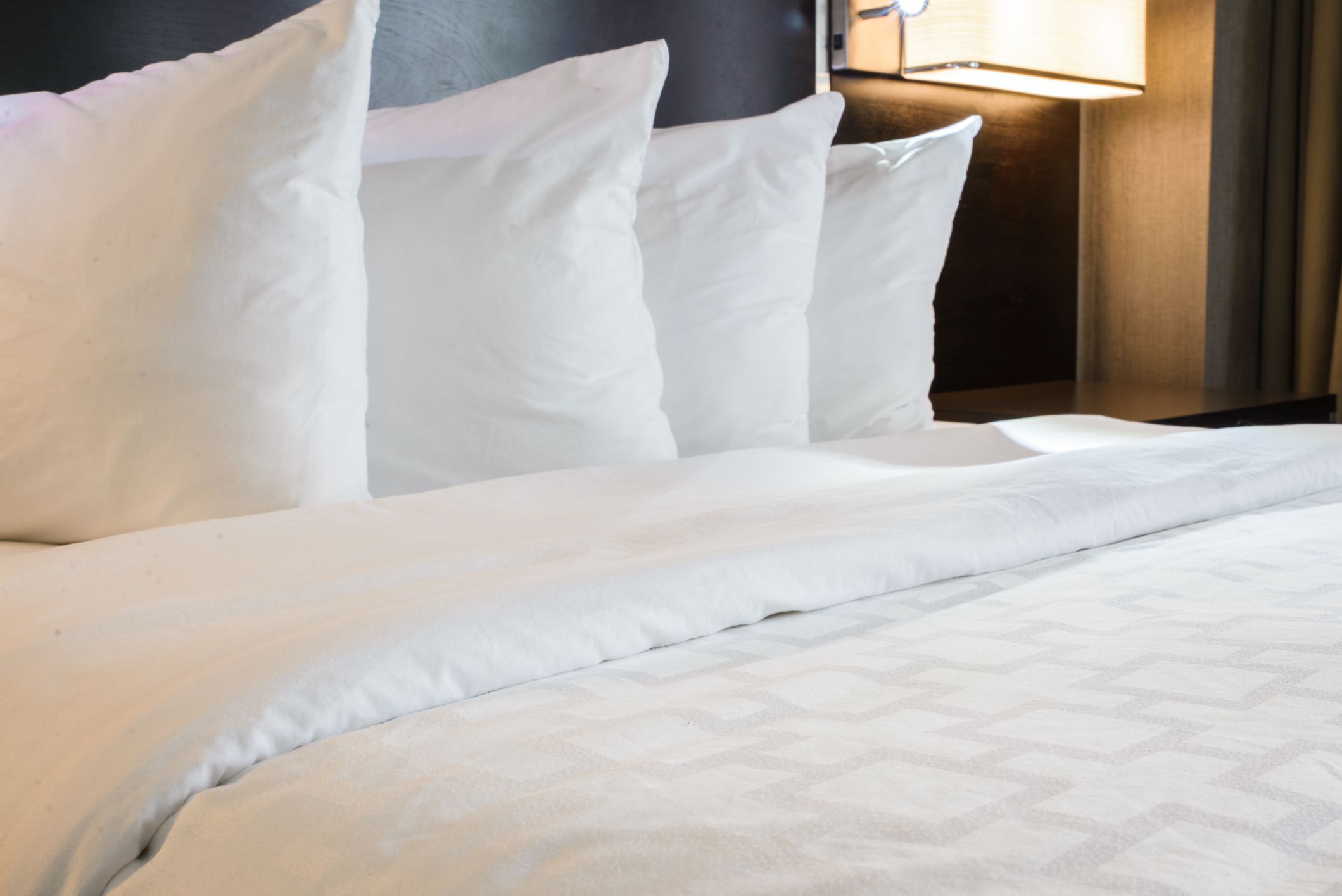 Neatly made hotel bed with 4 pillows.