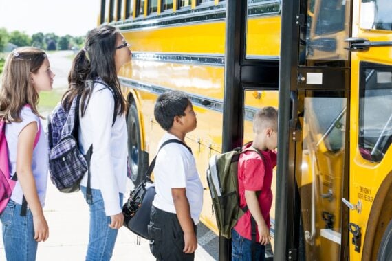 kids lined up tp get on schoolbus