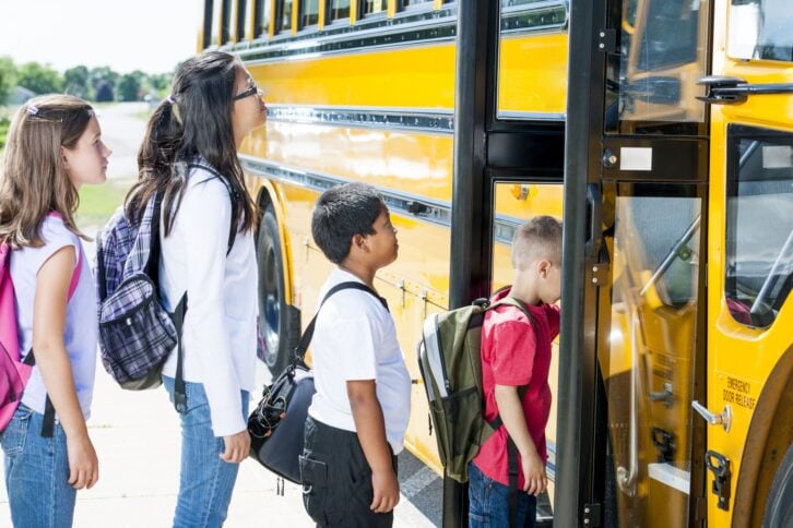kids lined up tp get on schoolbus