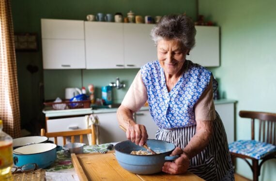 Senior woman baking pies in her home kitchen.  Mixing ingredients.