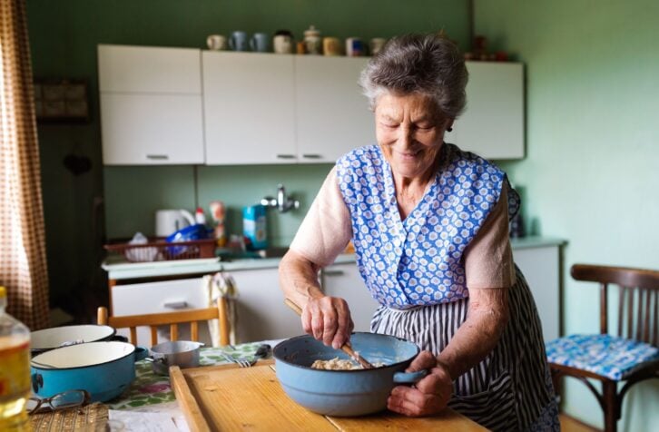 Senior woman baking pies in her home kitchen.  Mixing ingredients.
