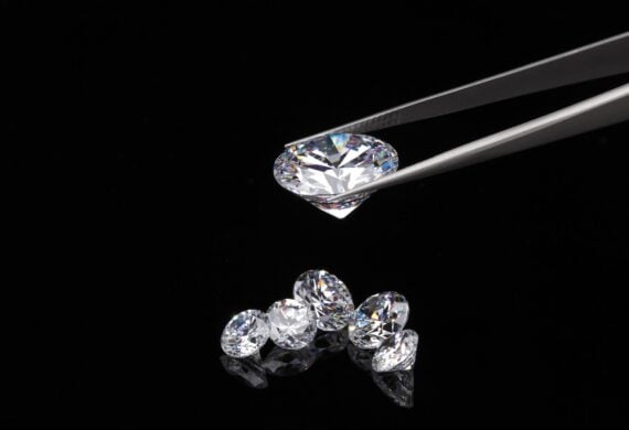 A round brilliant cut diamond held in tweezers